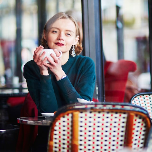 Young elegant woman drinking coffee in cafe in Paris, France