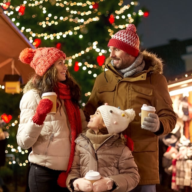 family with takeaway drinks at christmas market